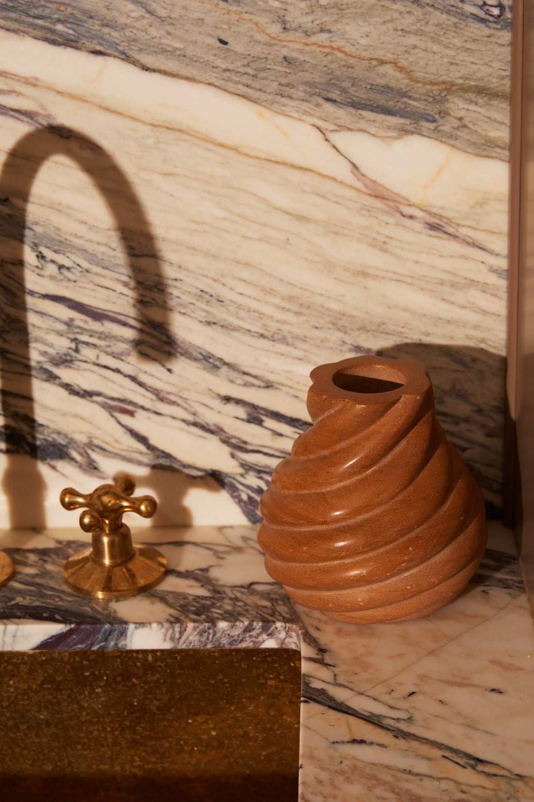 Small Swell Vase in Honeycomb beside a brass faucet on a veined marble counter