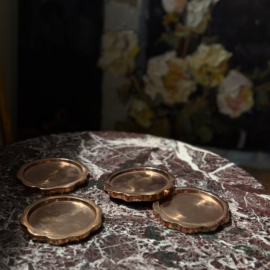 Sun Coaster Set in Pure Flame, four scalloped copper coasters on a red marble table