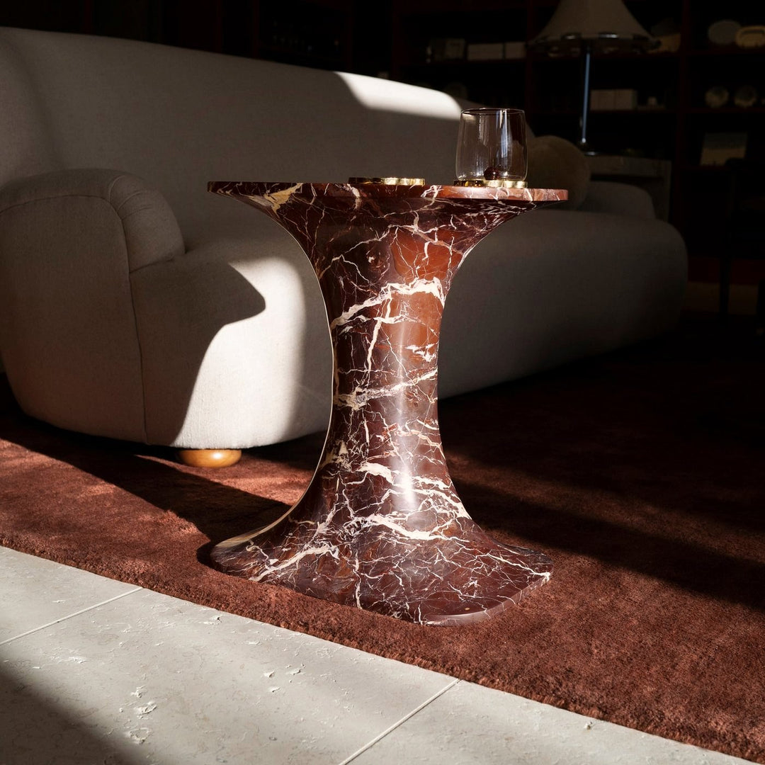 Norma Table in Cherry Gold marble beside a cream sofa on a rust rug