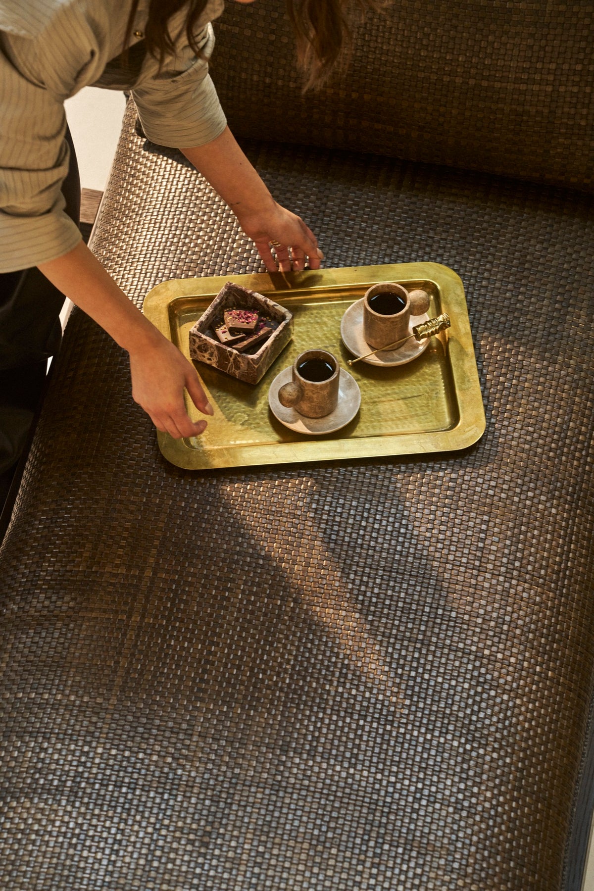 A brass tray of marble cups set down on a woven daybed
