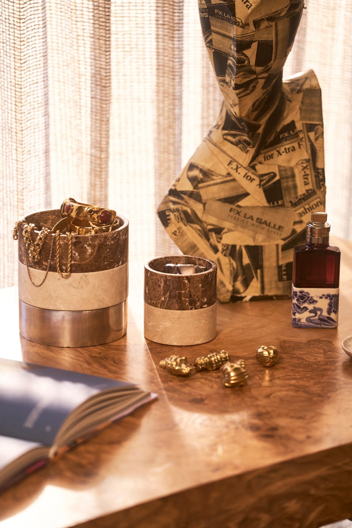 Stacked stone and aluminum boxes holding gold jewellery on a desk