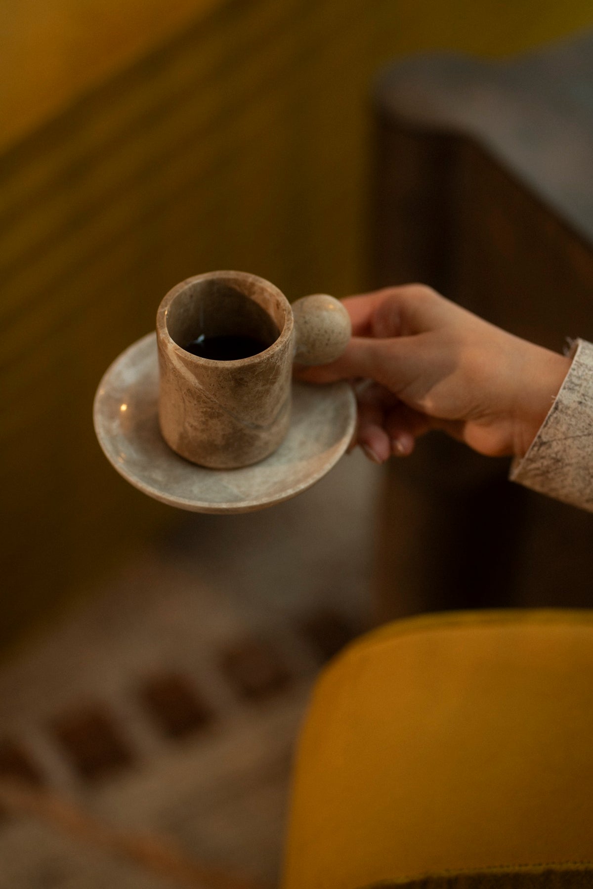 A hand holding a marble cup and saucer