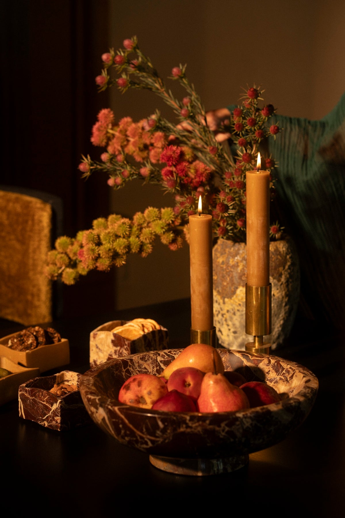The Centerpiece Bowl in Cherry Gold marble filled with pomegranates between tall candles and orange flowers