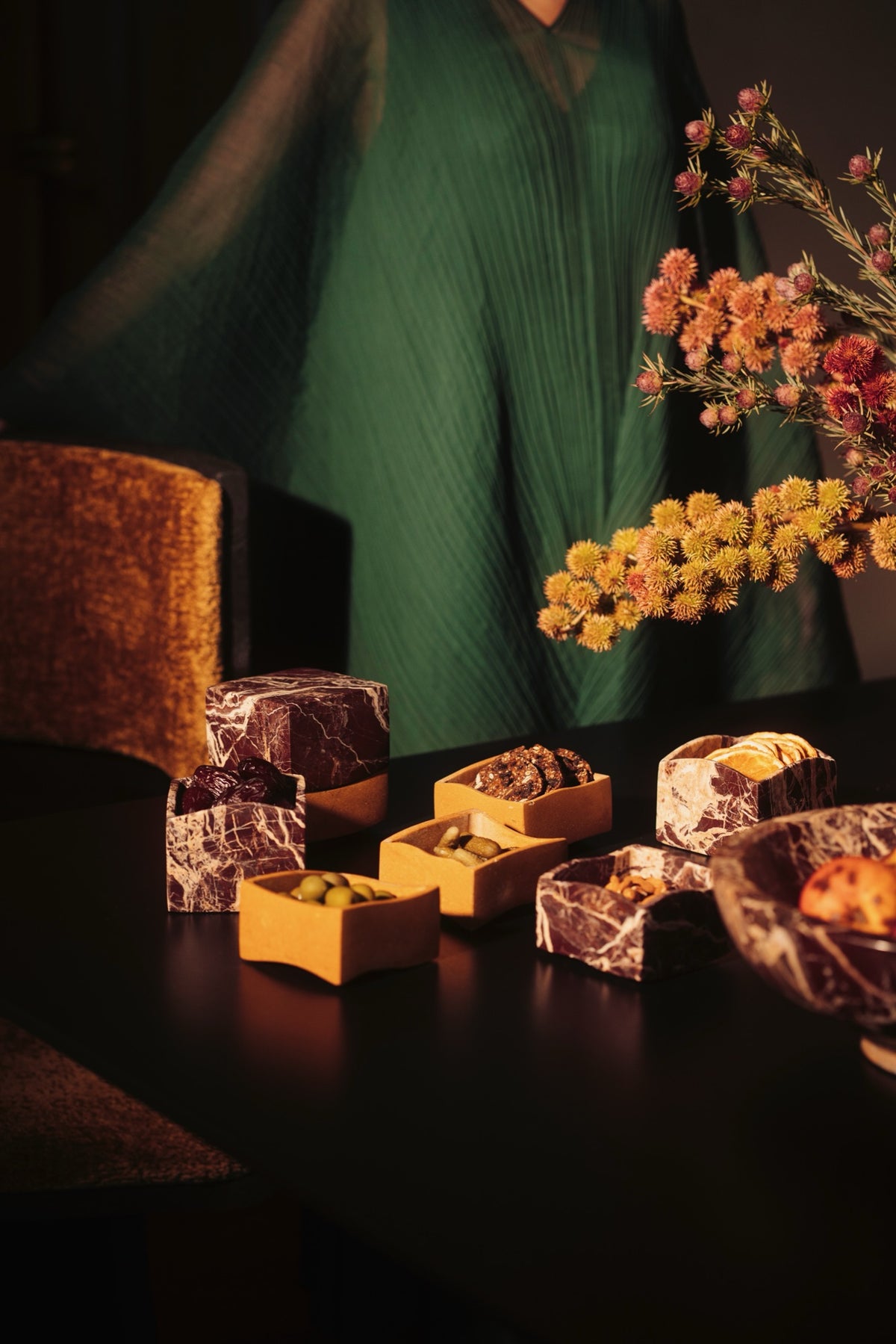 Red marble mezze boxes filled with olives on a dark table
