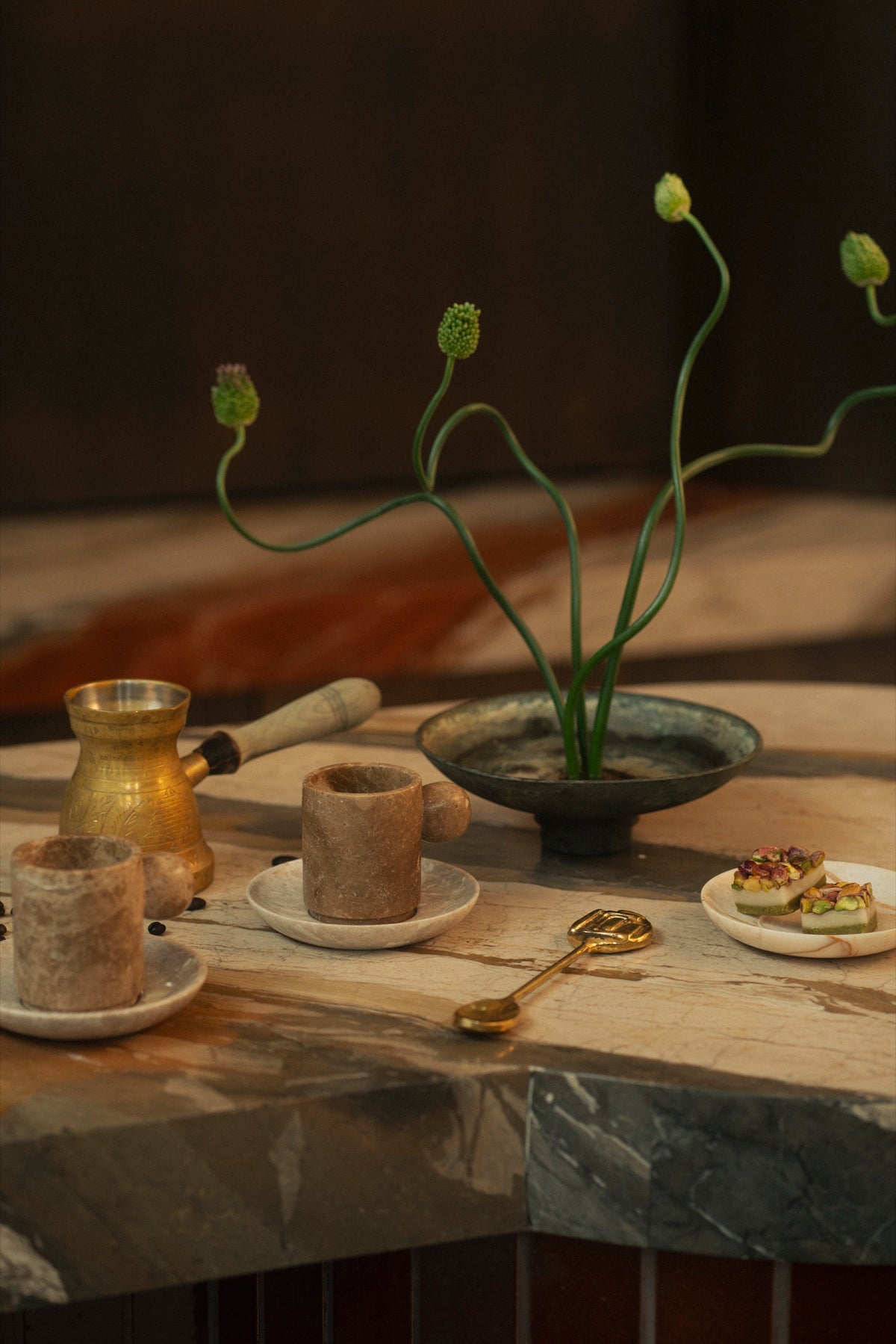 Marble cups, a brass coffee pot and a flower arrangement on the marble bar