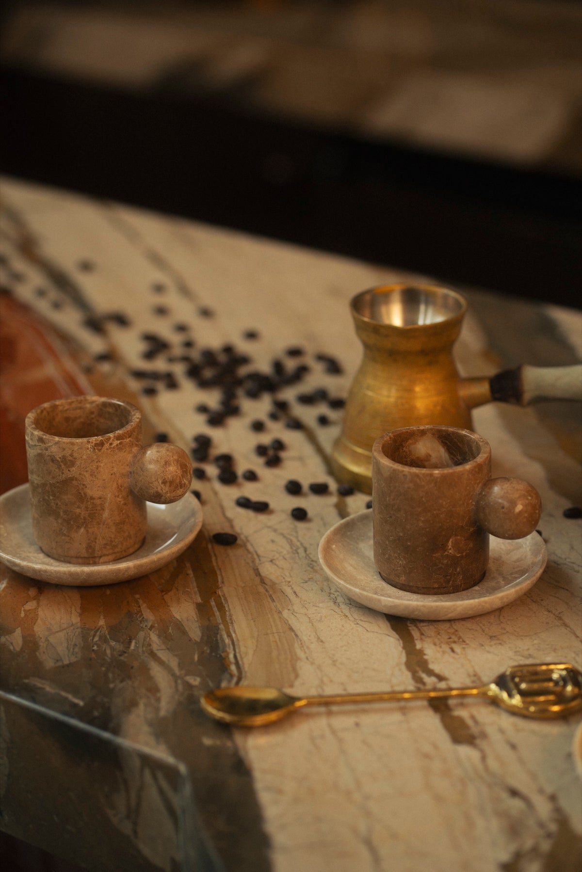 Marble cups and scattered coffee beans on a stone counter