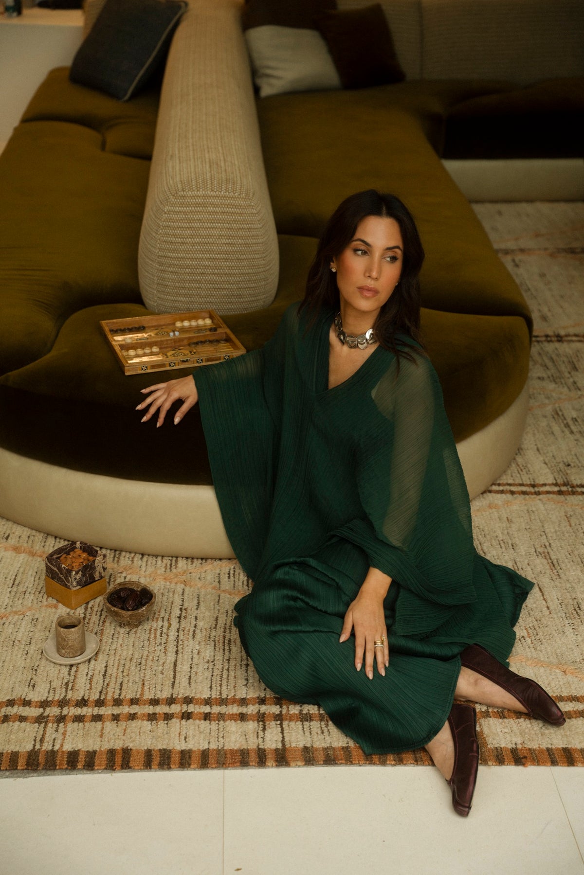Tania Sarin in a green dress seated on a woven rug