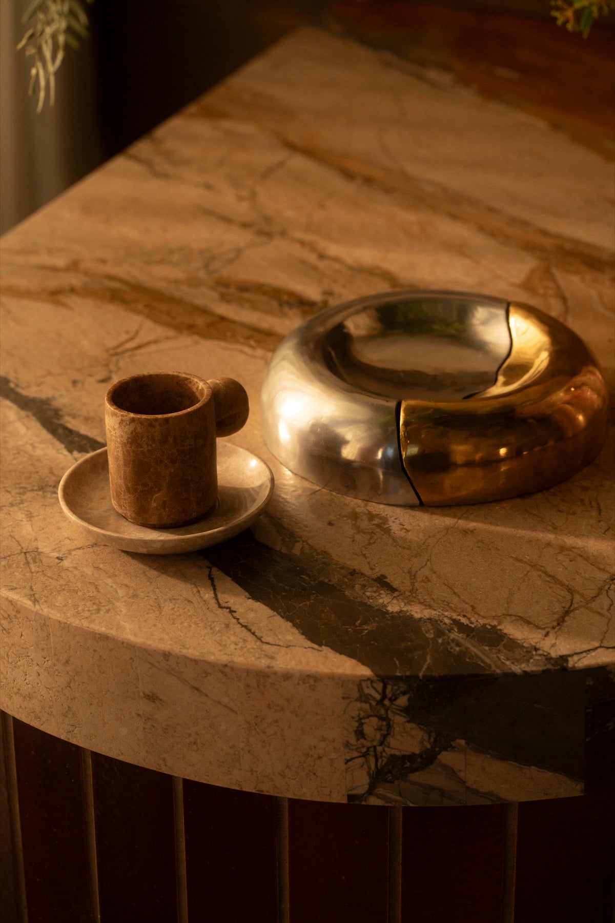 The Fusion Bowl in brass and aluminum beside a marble cup on the edge of the marble bar
