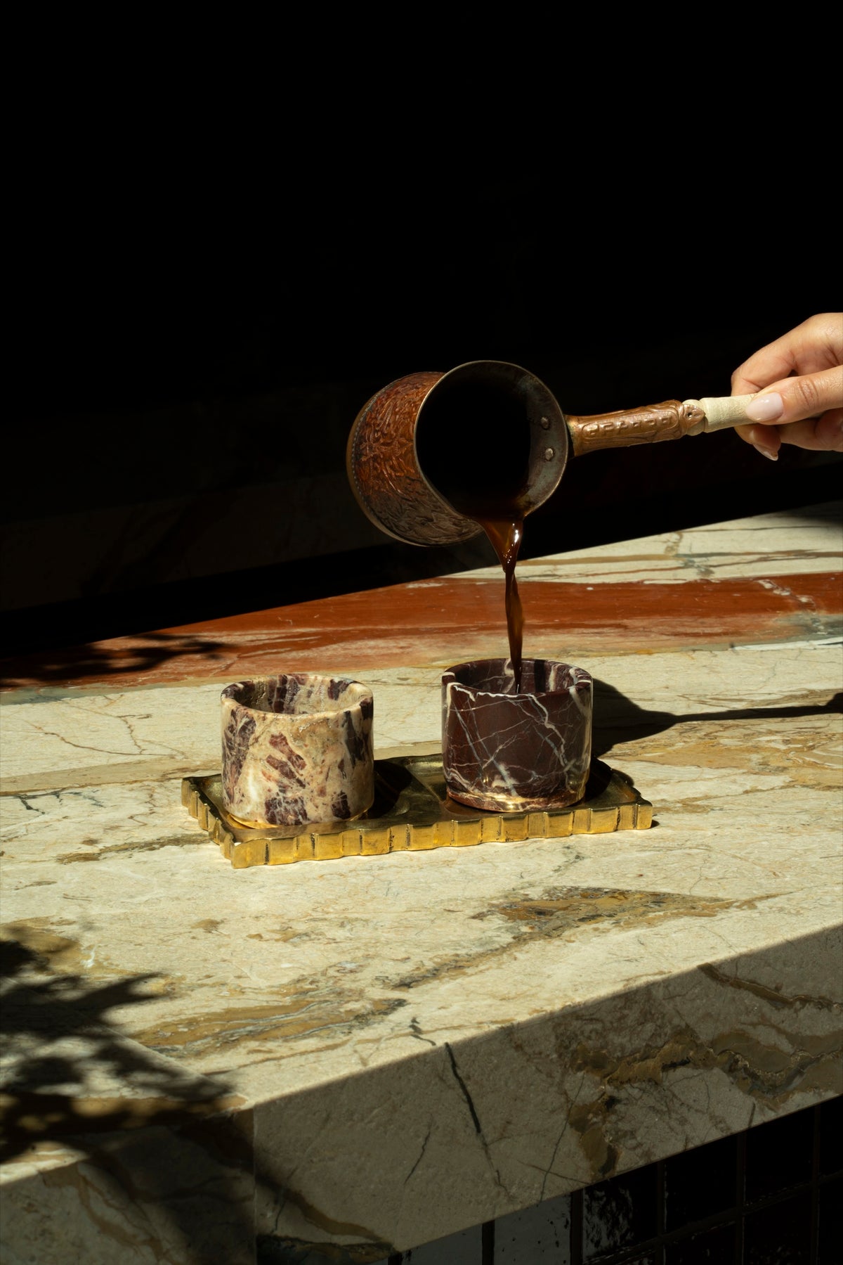 A thin stream of coffee poured into a Cherry Gold marble cup