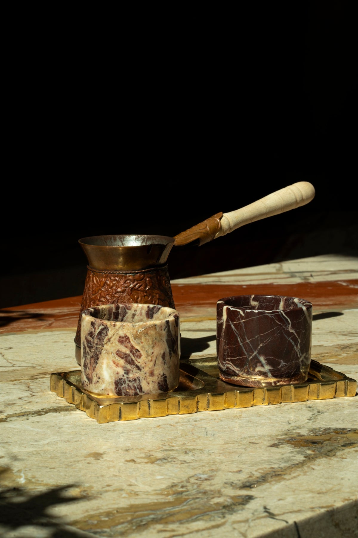 A copper coffee pot beside two Cherry Gold cups on a brass tray