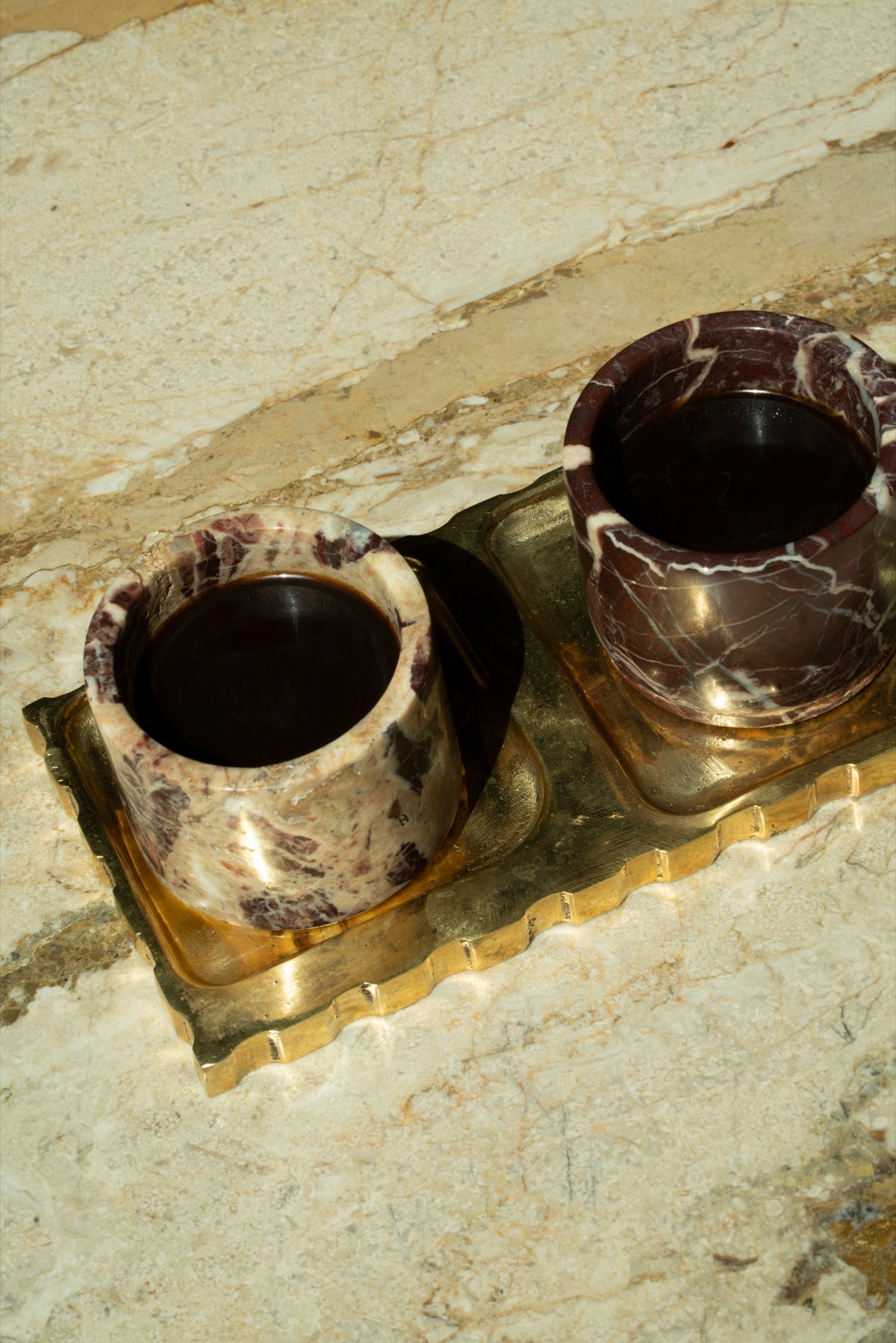 Two filled Cherry Gold cups on a scalloped brass tray, close up