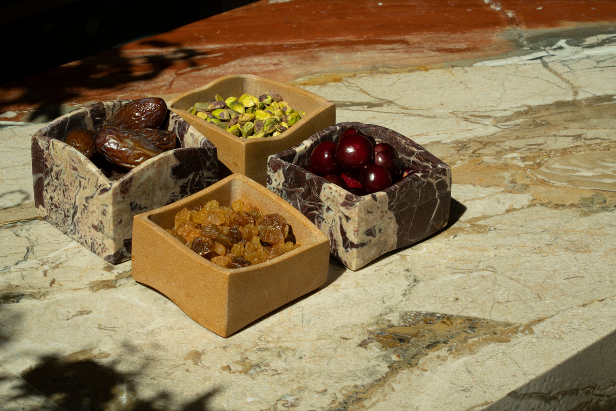 Four mezze boxes on the marble bar with leaf shadows