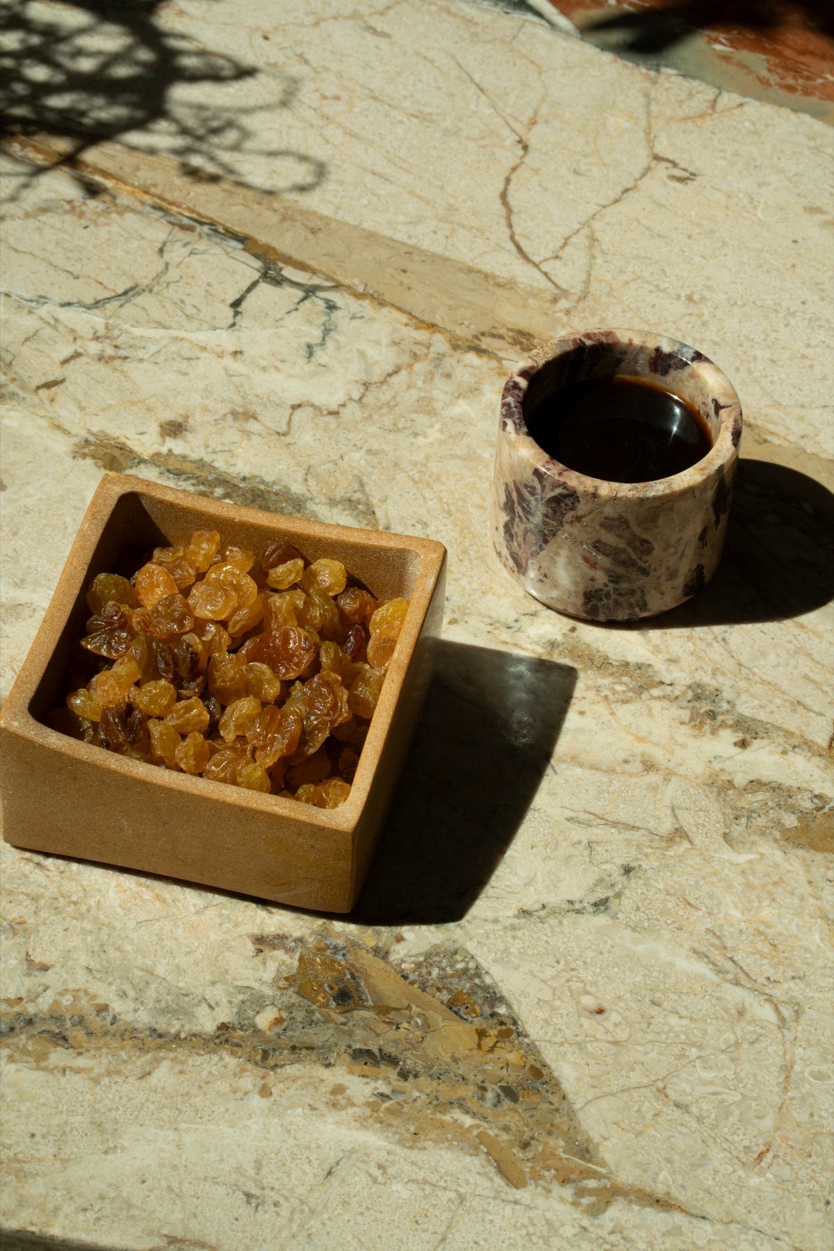 A box of golden raisins and a cup of coffee on the marble bar