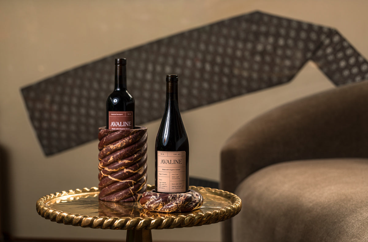 Wine Coaster and Wine Chiller in Cabernet Red Marble with two bottles of Avaline red wine on a brass side table