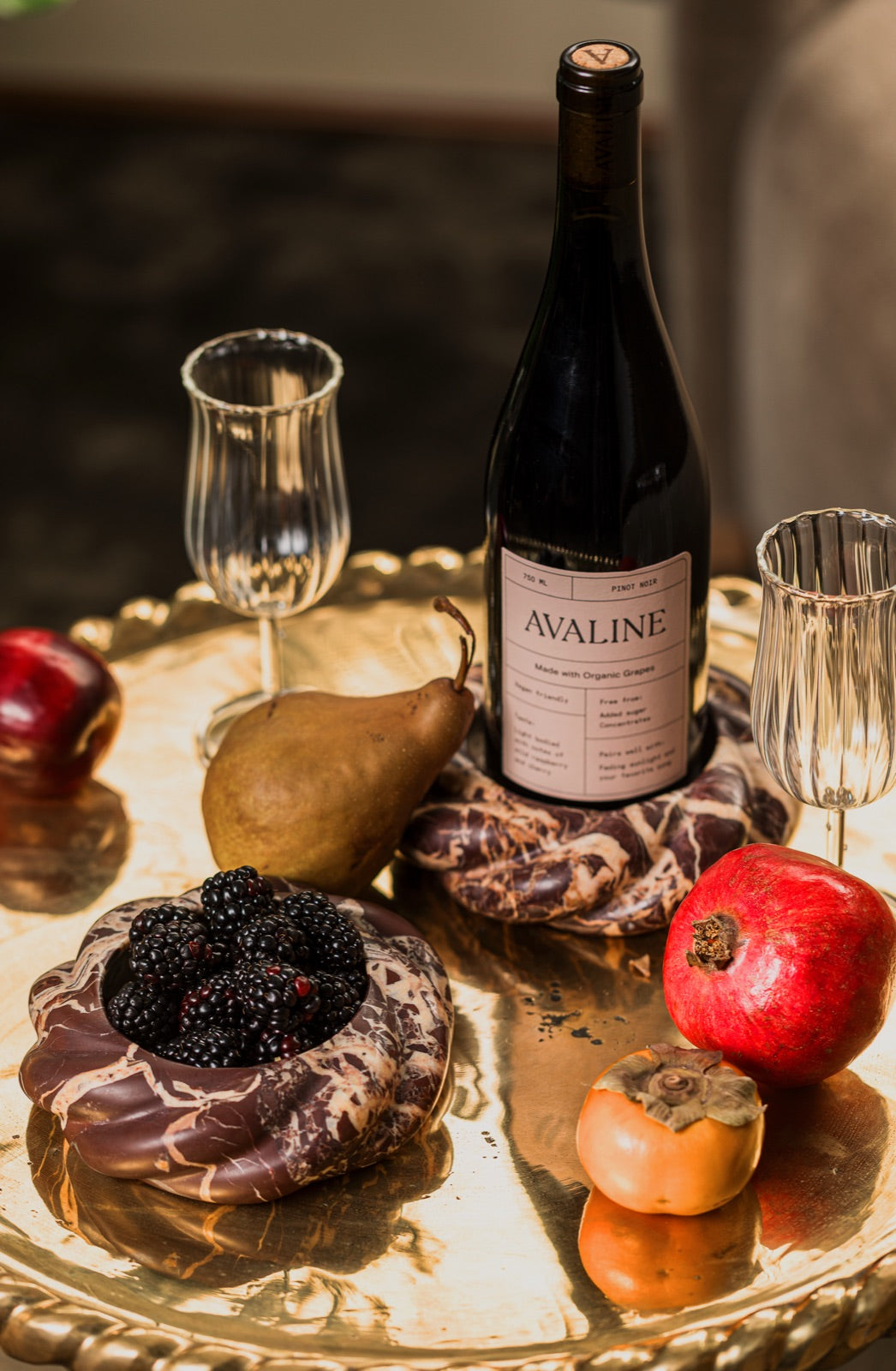 Wine Coasters in Cabernet Red Marble with a bottle of Avaline red wine, blackberries, a pear, a pomegranate and persimmons on a brass tray
