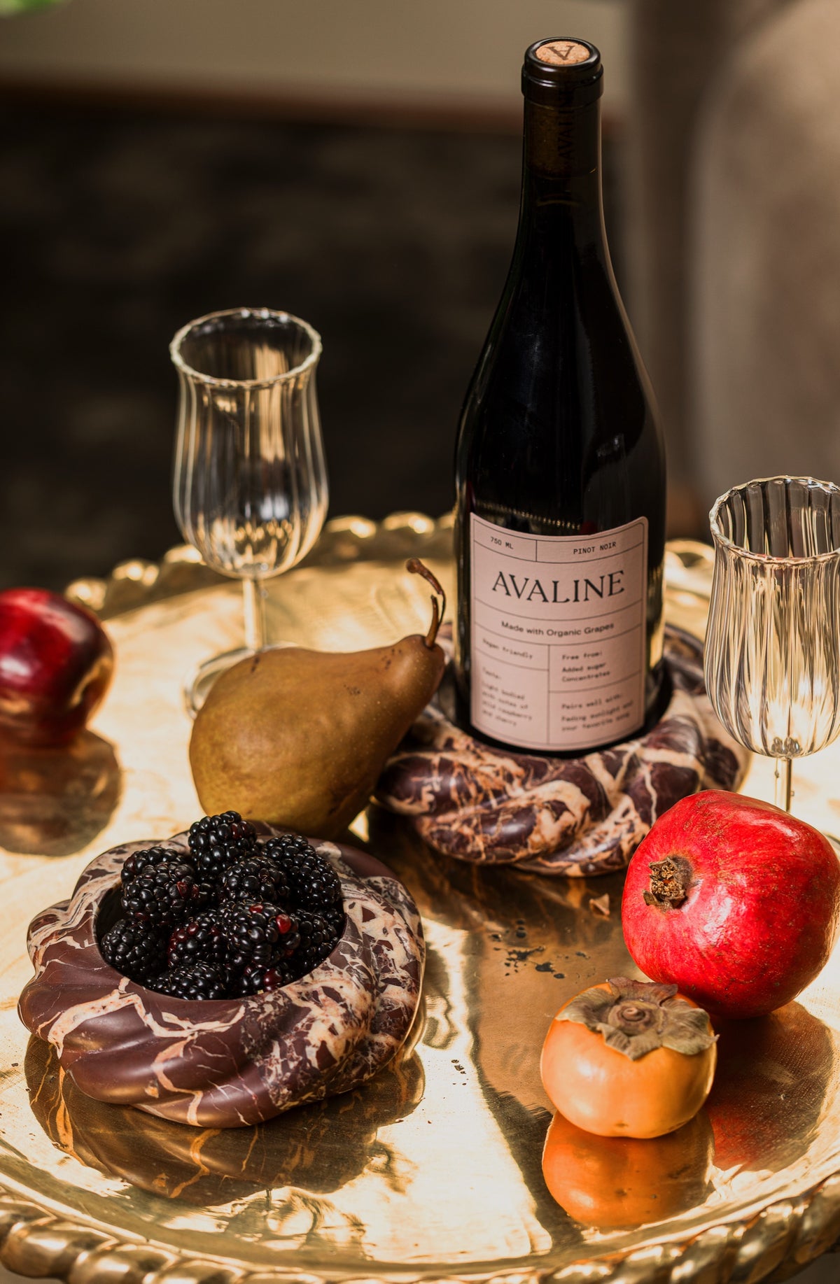 Wine Coaster in Cabernet Red Marble holding a bottle of Avaline red wine beside a coaster of blackberries