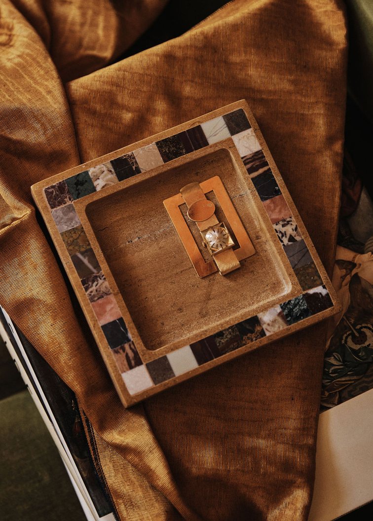 The Mini Klee Catch in Honeycomb, its rim inlaid with a checkerboard of stones, holding a gold watch on ochre silk