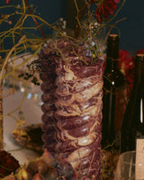 Tall Swell Vase in Cherry Gold with branches and dark red dahlias
